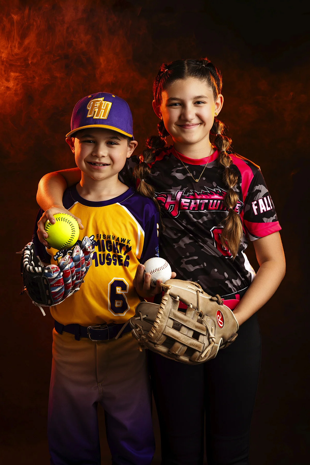Baseball and softball siblings posing with fire background