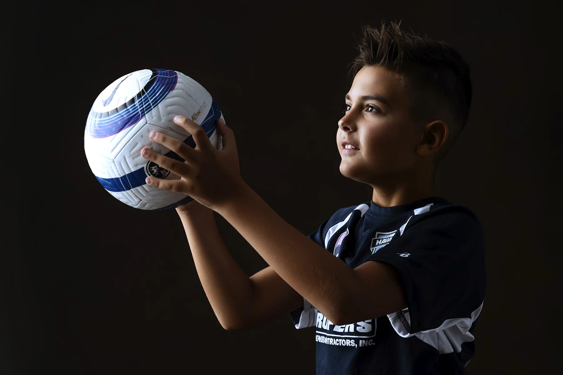 Soccer player holding ball with dramatic studio lighting