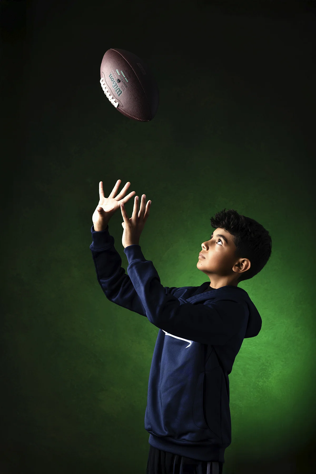 Football player catching a tossed ball in green studio light