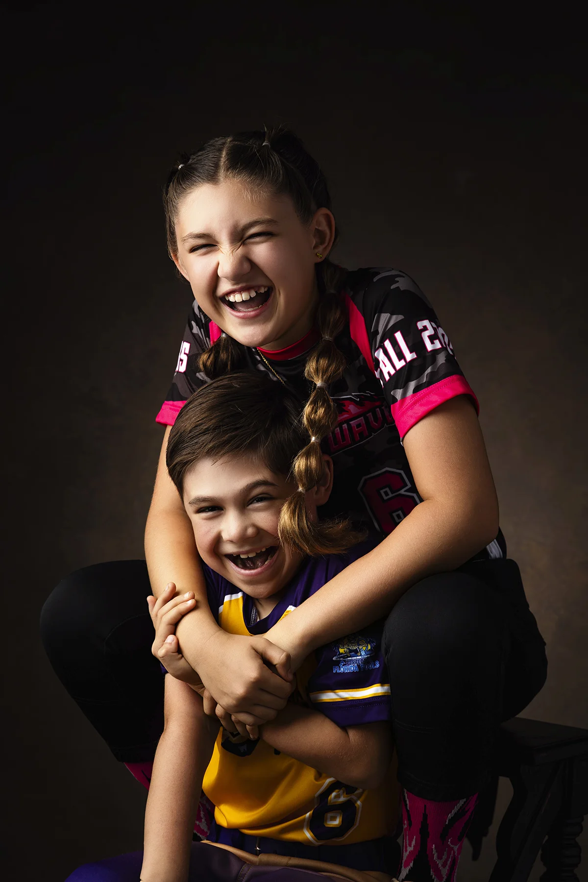 Softball siblings laughing together in sports portraits