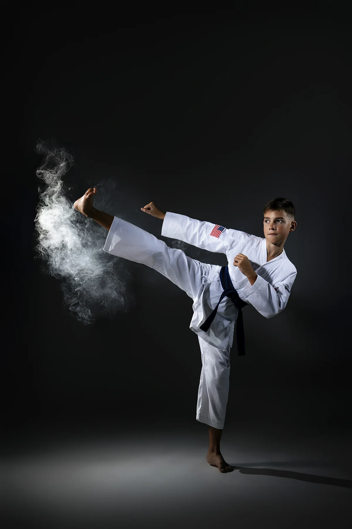 Taekwondo athlete executing high kick with smoke effect