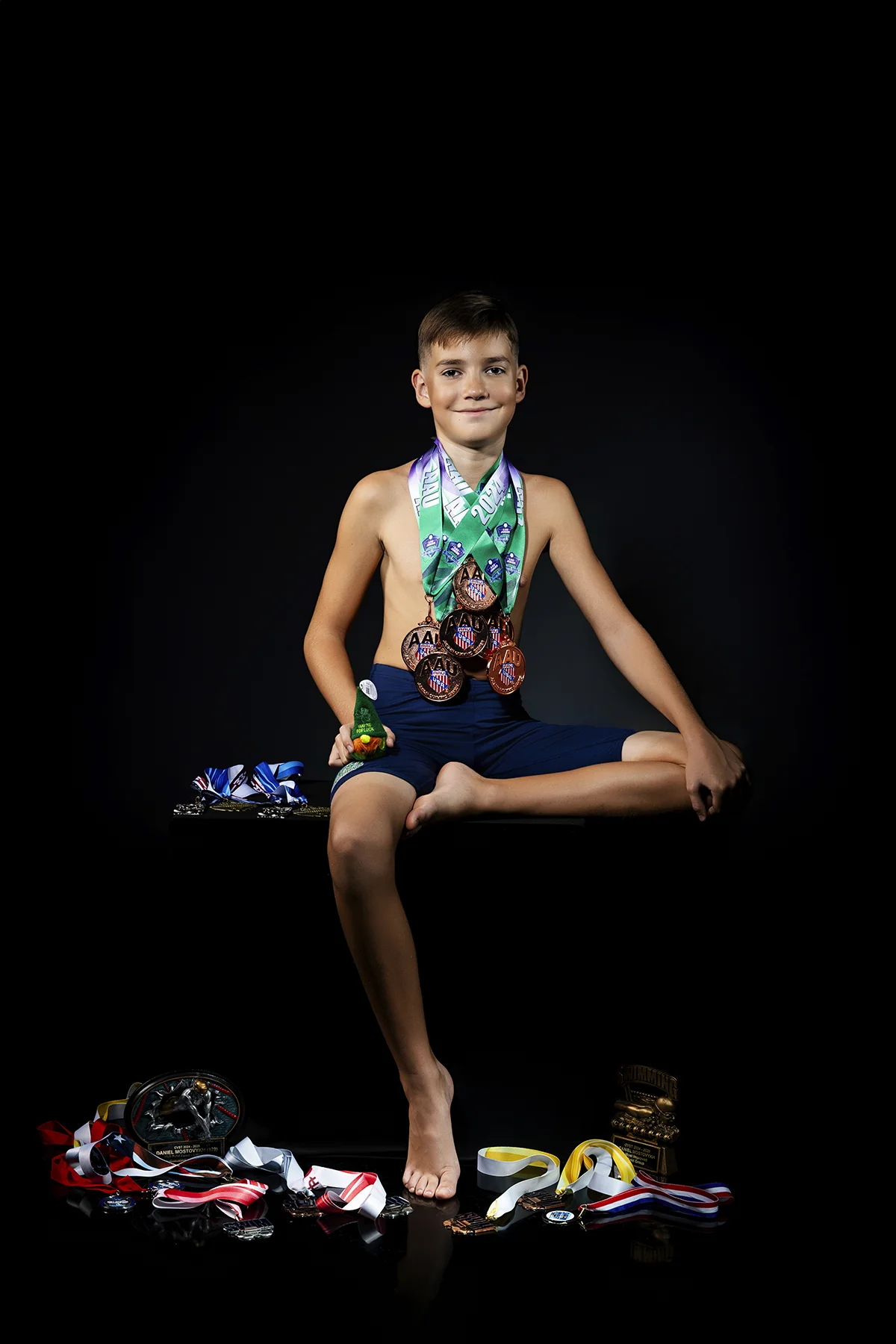 Young swimmer seated with collection of medals