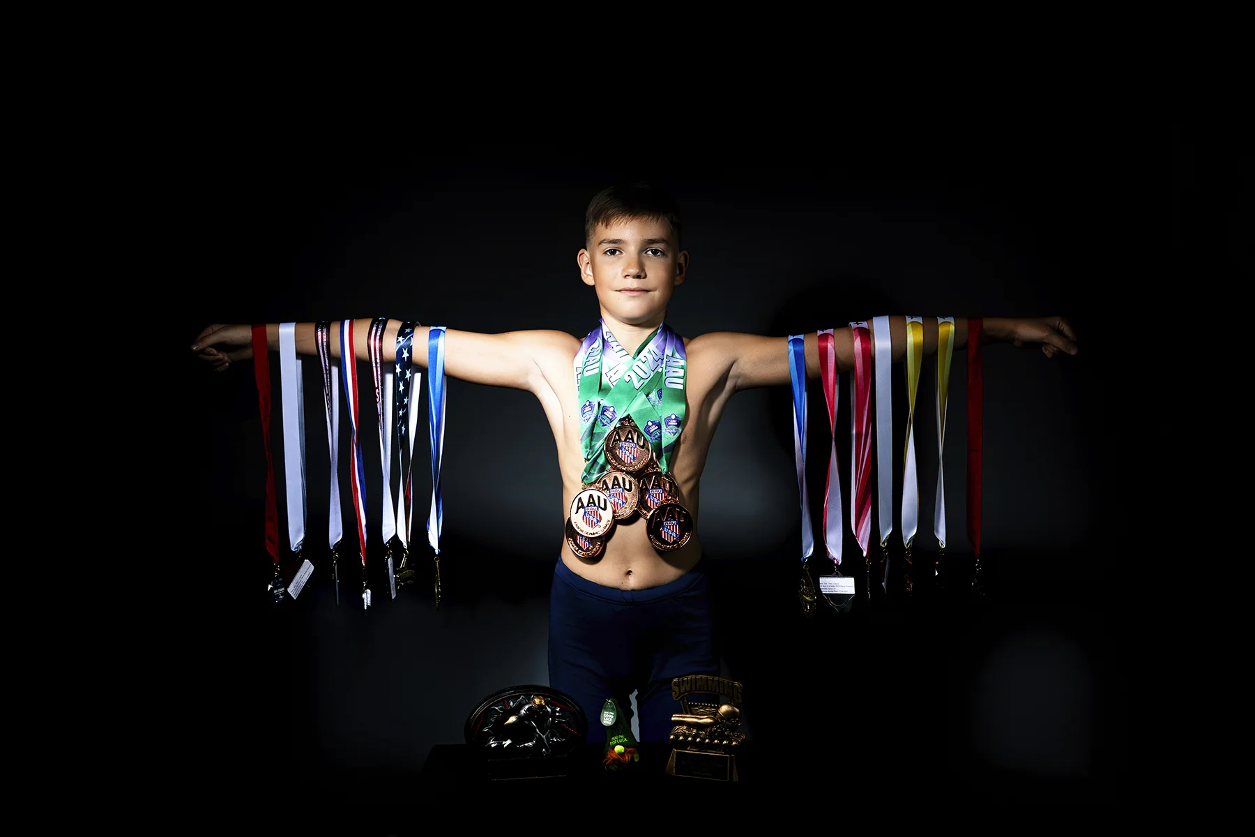 Swimmer displaying championship medals with arms outstretched