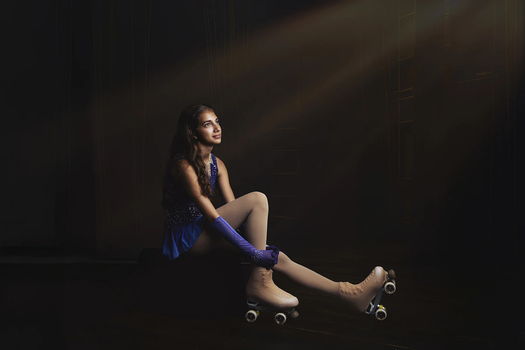 Roller skater girl in sparkly costume under dramatic spotlight