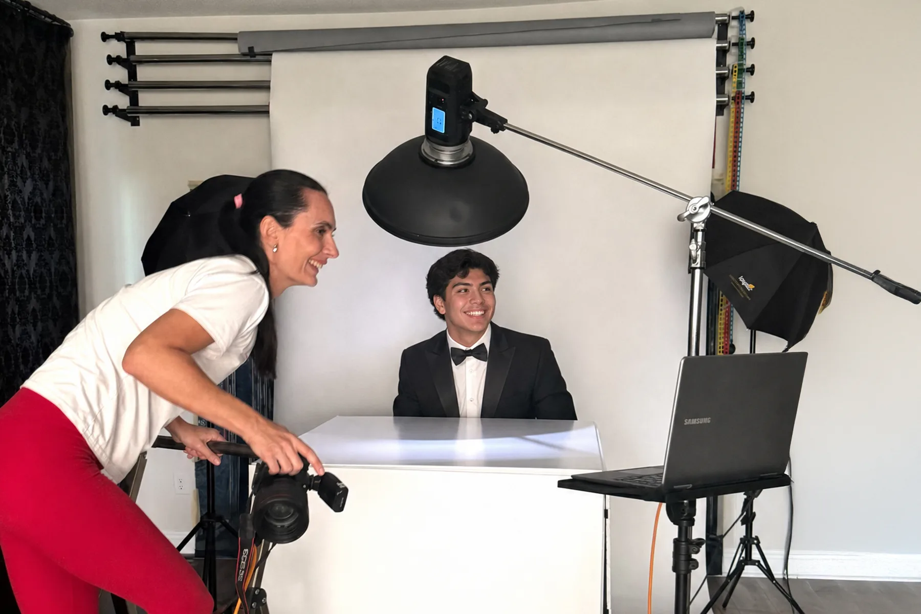 Photographer guiding a senior in a tuxedo during a studio session, behind the scenes