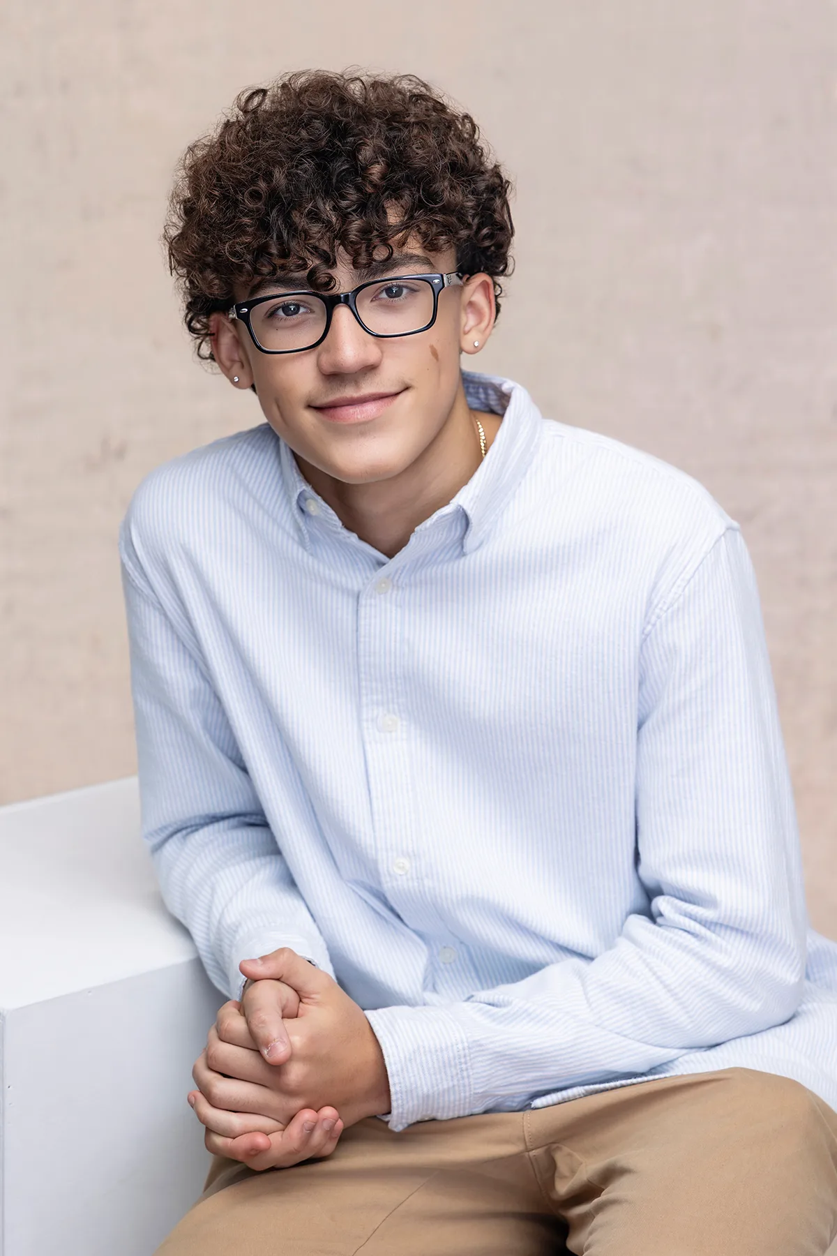 Senior in a light blue button-down shirt and glasses, seated classic portrait